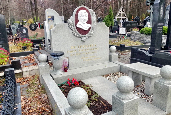 Простой памятник с барельефом покойной в рамке